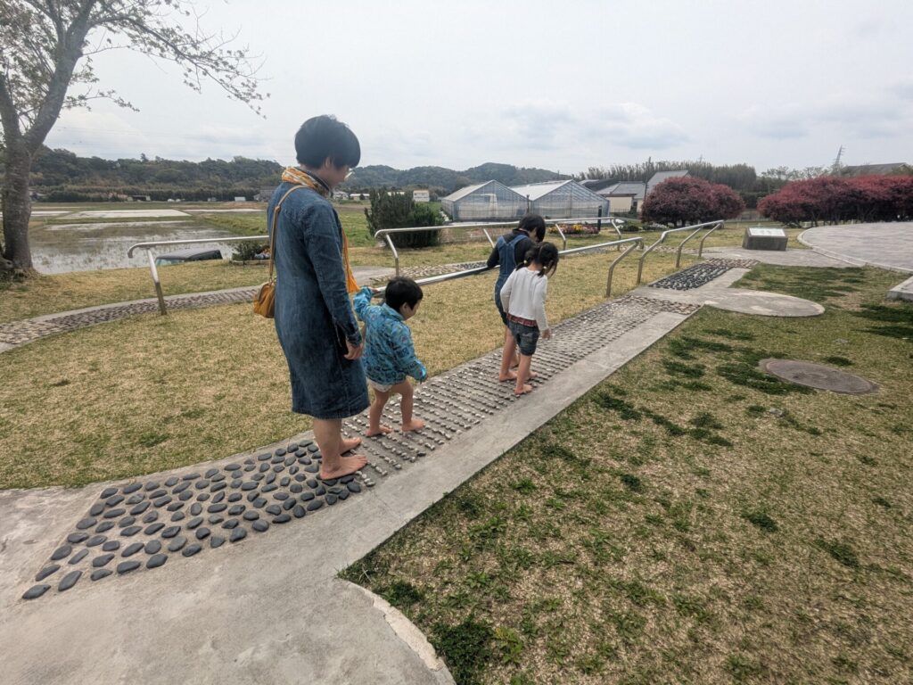 三好村の足湯の隣にある足つぼ刺激をする道を歩く親子